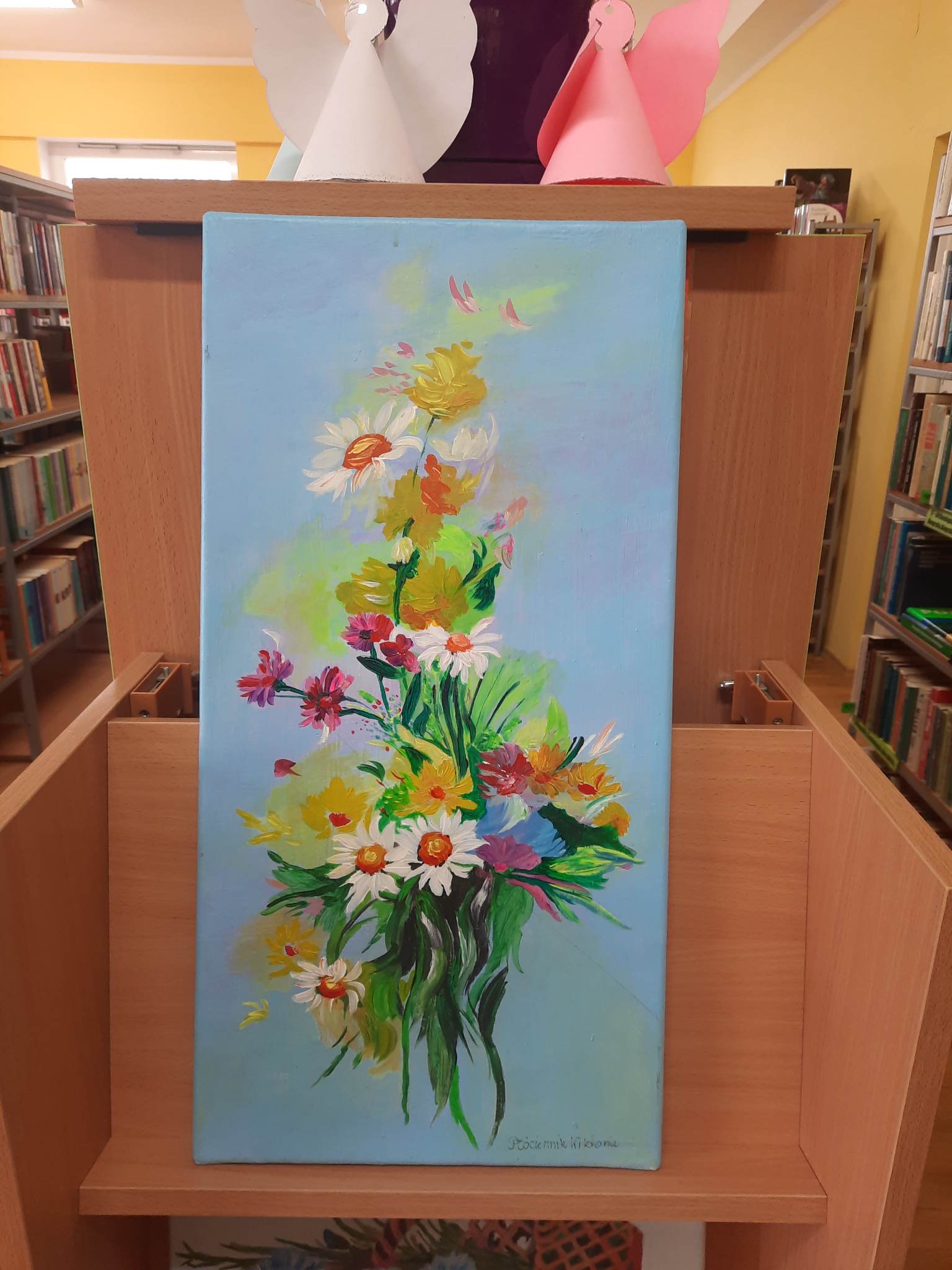 Obraz autorstwa pani Wiktorii Płóciennik przedstawiający kolorowy bukiet kwiatów na niebieskim tle