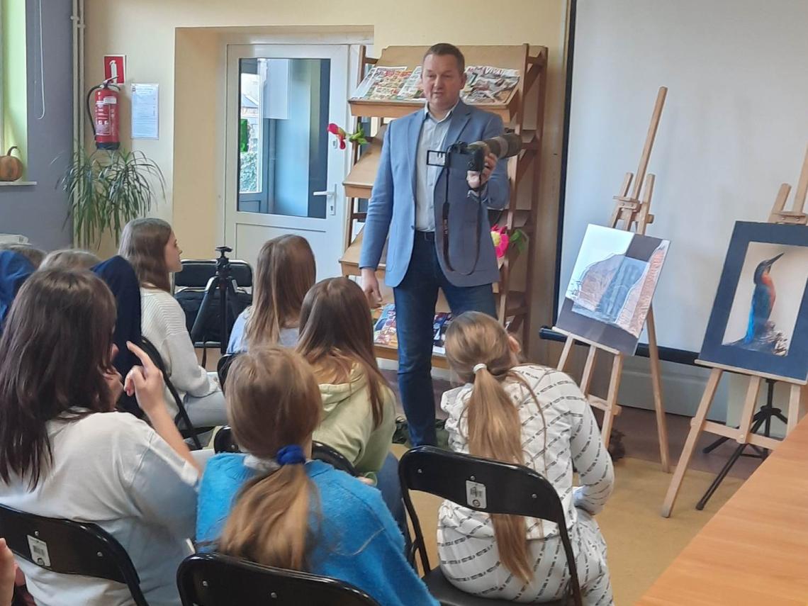 Uczniowie szkoły podstawowej w Pomianowie z autorem wystawy  fotografii Przyroda naszego regionu w miejscowej bibliotece