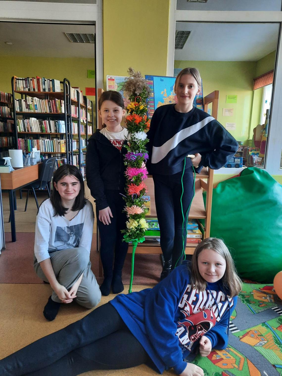 Uczestnicy warsztatów wielkanocnych z wykonaną palmą wielkanocną z kolorowymi kwiatkami z bibuły w filii w Pomianowie