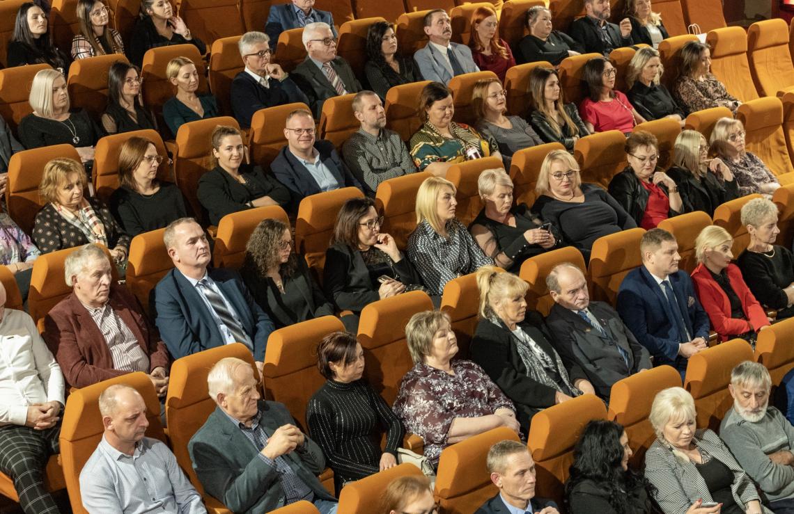 fragment widowni. Fotele, na których siedzą kobiety i mężczyźni.